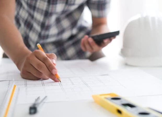 Engineering blueprints, calculator, level, compass and safety helmet