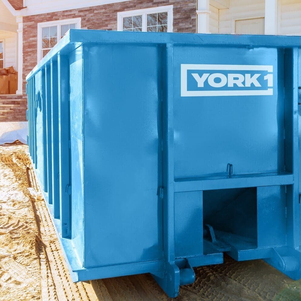 YORK1 dumpster bin sits in front of a house undergoing renovations, ready to collect construction debris."